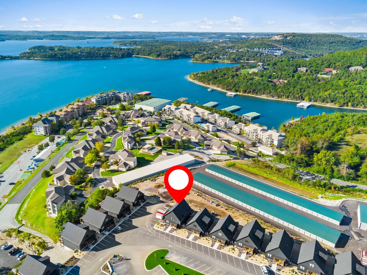 A scenic exterior perspective showing the lake, residential buildings, surrounding greenery, and docks. The image evokes a sense of adventure and flexibility, highlighting opportunities for boating, waterfront dining, or simply soaking up the sunset views over the water.