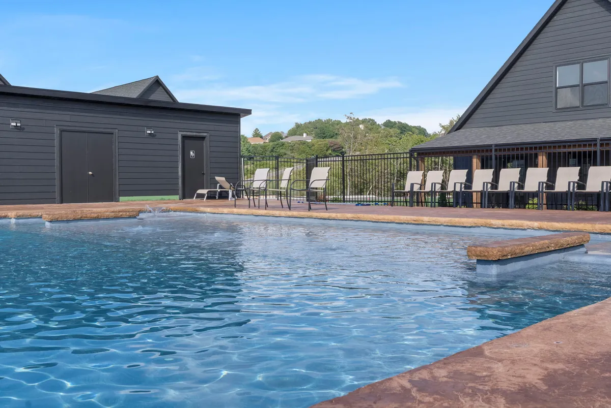 A sparkling outdoor swimming pool surrounded by lounge chairs and a contemporary building facade. The scene is bathed in warm, sunset light, suggesting welcoming social spaces and opportunities for outdoor enjoyment.