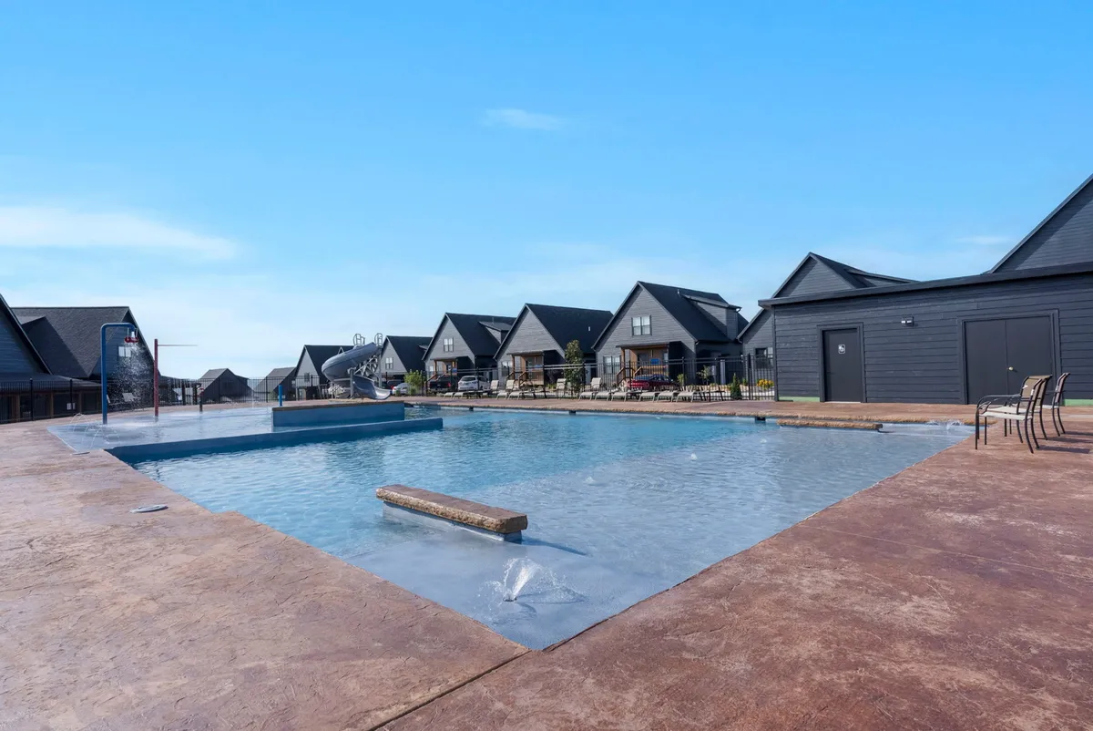 A tranquil exterior view of the swimming pool with lounge chairs arranged along the water's edge and the retreat's buildings in the background. The setting sun casts a warm glow over the eco-friendly architecture, inviting guests to relax after a day of local exploration.