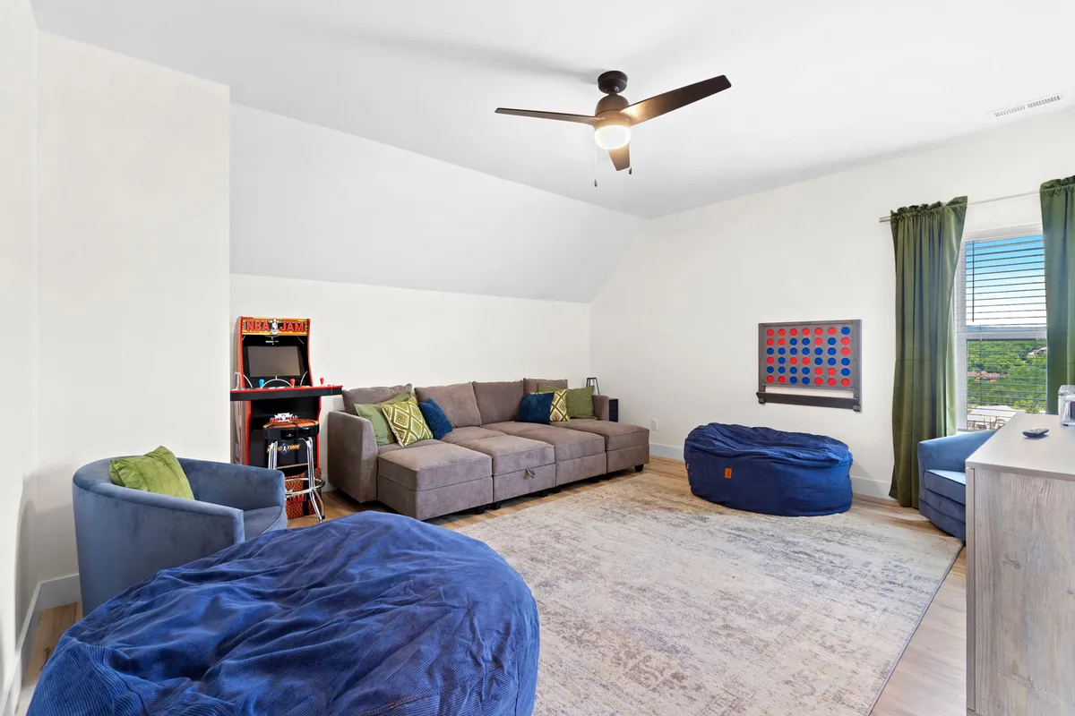 A bright, playful game room featuring a comfortable sofa, bean bags for lounging, colorful wall art, and a ceiling fan. The space feels youthful and inviting, ideal for socializing, playing games, and relaxing after a day of adventure.