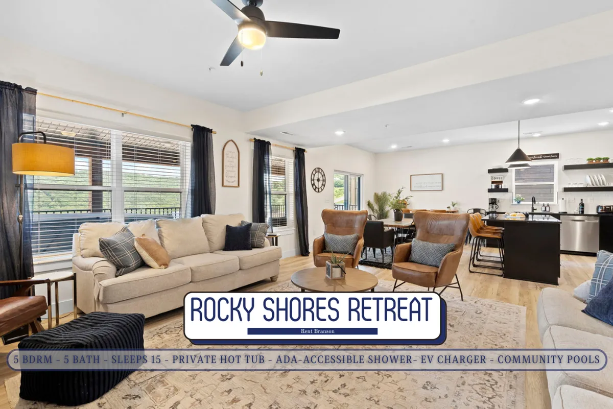 A comfortable living area with plush seating, large windows streaming in natural light, and the kitchen visible in the background. The decor is inviting, with touches of wall art and decor that amplify the home's cozy, communal vibe.